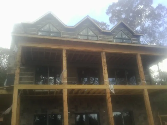 Dormers and porch framing on a large log home under construction — Roof Coating work by our crew in Flomaton