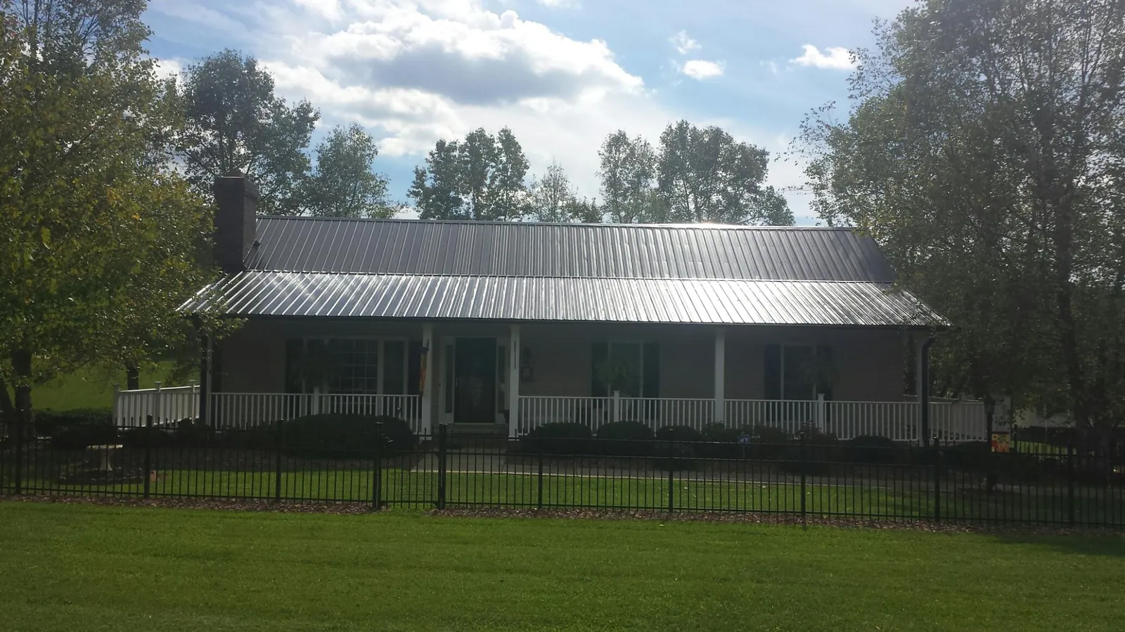 Gray metal roof on a brick ranch with a full width front porch — Gutter Guard Installation work by our crew in Flomaton